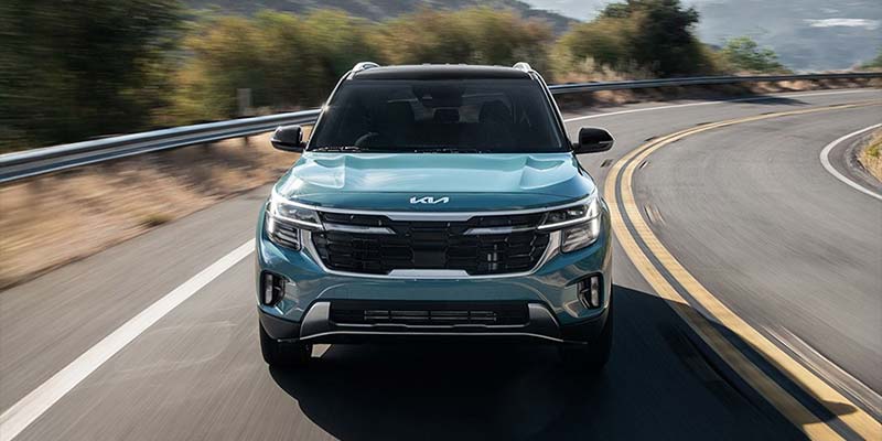 2026 Kia Seltos driving on a winding road, showcasing its sleek front design and dynamic performance